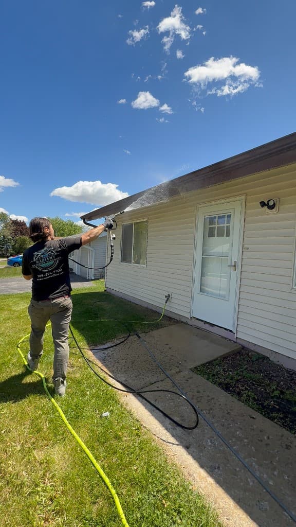 Radiant Exterior Cleaning washing roofline and gutters on a residential home, Emerald Coast exterior cleaning